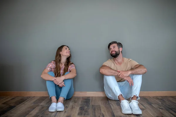 Jovem casal sentado no chão em nova casa — Fotografia de Stock