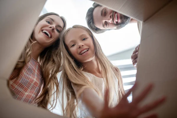 Familia feliz abriendo un cartón y mirando emocionado — Foto de Stock