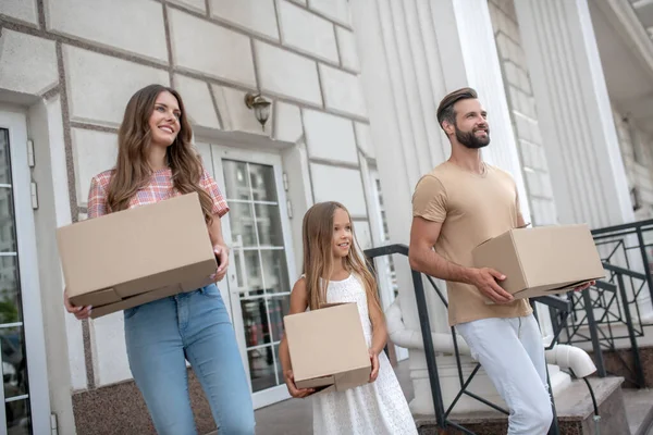 Joven familia llevando cartulinas y lista para moverse — Foto de Stock