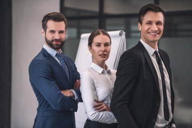 Kahverengi saçlı kadın ve iki erkek iş arkadaşı yarı yolda duruyor.