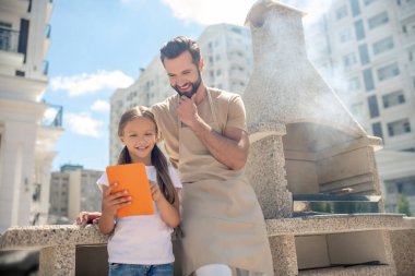 Baba ve kızı tabletten bir şey izliyorlar ve ilgileniyorlar.