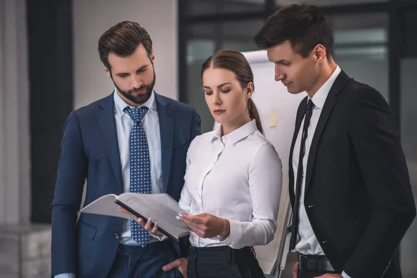 Brown-haired female showing papers to her male collegues — Stock Photo, Image