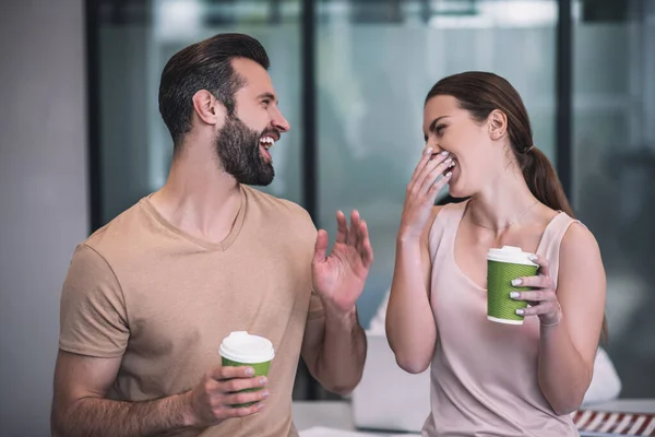 Compañeras de trabajo barbudas y de cabello castaño disfrutando del café, riéndose —  Fotos de Stock