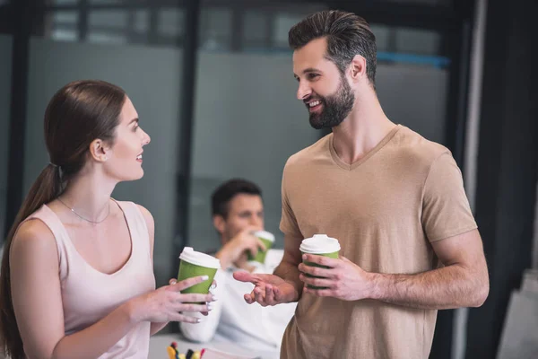 Earded male and brown-haired female colleorkers drinking coffee, smiling — стоковое фото