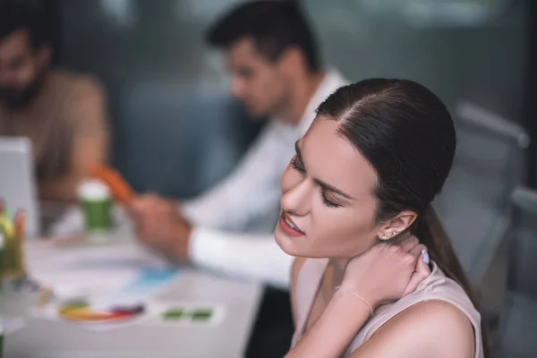 Mujer de cabello castaño cansada sentada en la reunión, estirando su cuello — Foto de Stock