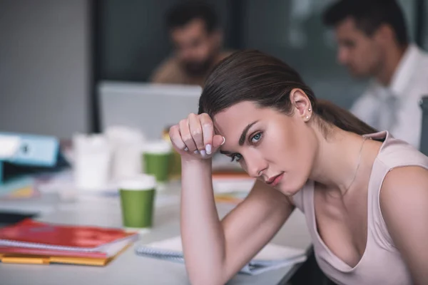 Mujer morena agotada sentada en la reunión, apoyando la cabeza sobre la mano — Foto de Stock