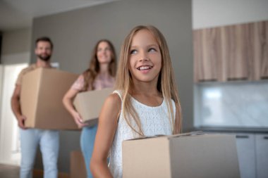 Uzun saçlı, güzel bir kız, elinde kartonla gülümsüyor.