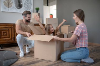 Kutuda oturan ve ailesine gülümseyen tatlı bir kız.