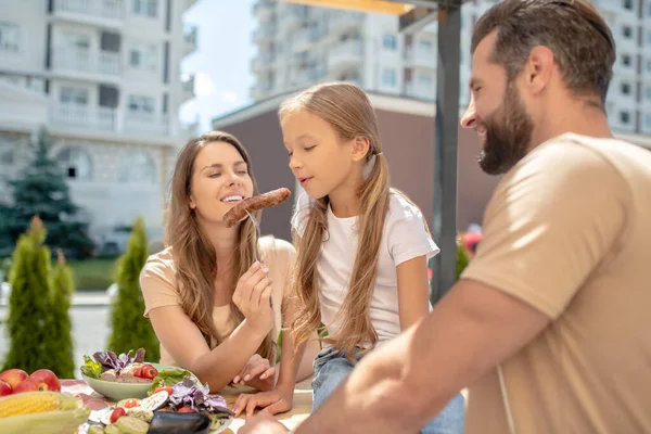 Jovem família jantando fora e olhando alegre — Fotografia de Stock