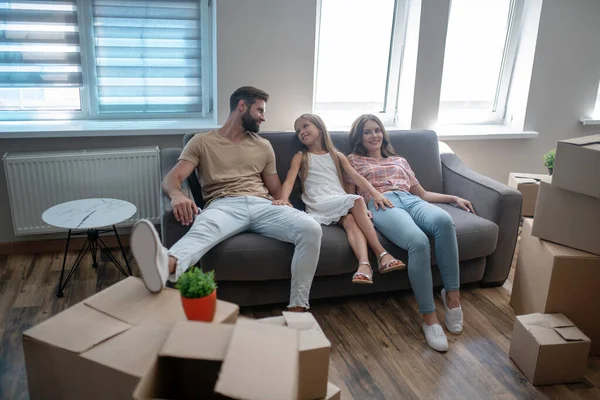 Семья отдыхает на диване после переезда в новый дом — стоковое фото