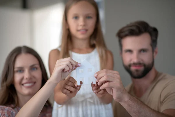 Familjen visar ett hem miniatyr och ser positiv ut — Stockfoto