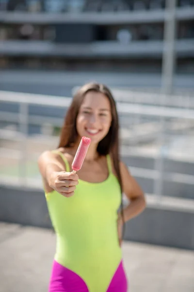 Flicka i ljusa sportkläder och rullskridskor visar glass — Stockfoto