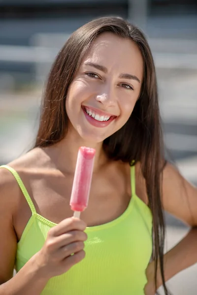 Fille en haut jaune souriant et tenant la crème glacée — Photo