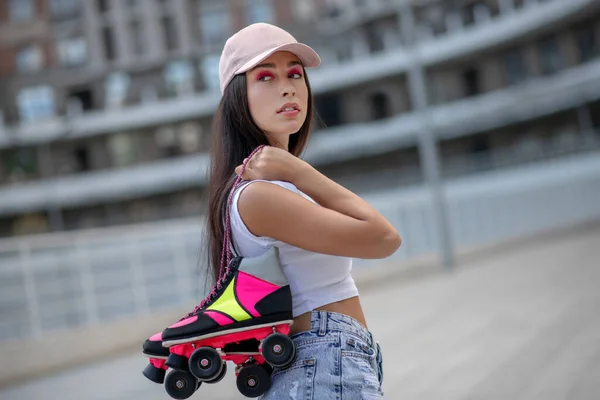 Linda chica en gorra llevando patines en las manos —  Fotos de Stock