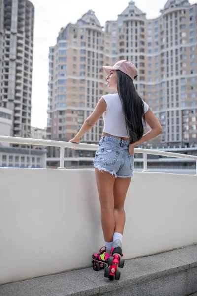 Slim dívka v džínách kraťasy a stojící v kolečkových bruslích — Stock fotografie