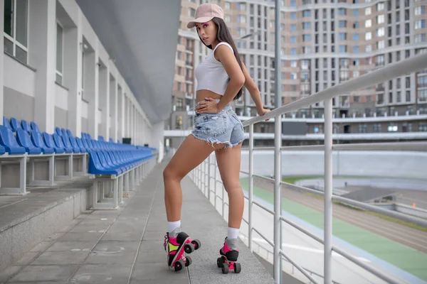 Fille aux cheveux bruns en jeans short et roller-skates posant — Photo