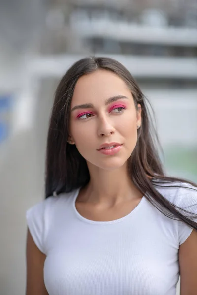 Donkerharig meisje in wit tshirt op zoek bedachtzaam — Stockfoto