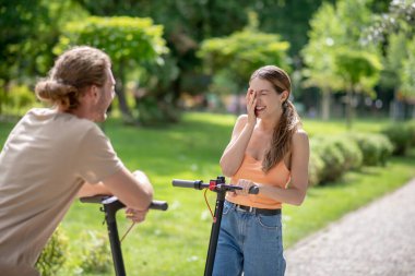 Motosikletli genç çift parkta iyi vakit geçiriyor.