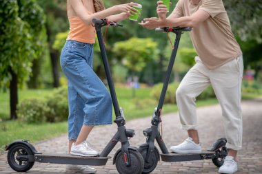 Parkta scooterlı iki kişi konuşuyor.