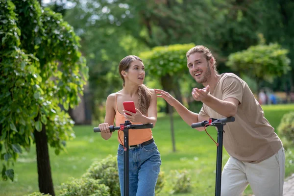 Young bearded man showing something to his girlfriend and looking excited — Stock Photo, Image