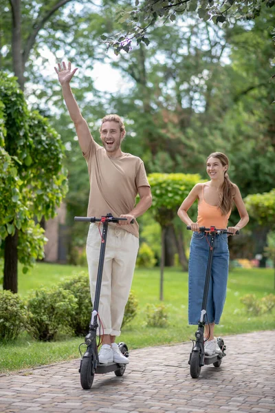 Jovens montando scooters no parque e olhando animado — Fotografia de Stock