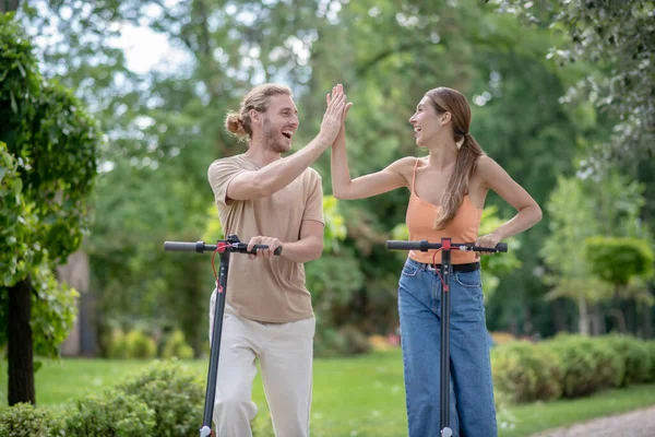 Junges Paar fährt Roller im Park und sieht glücklich aus — Stockfoto