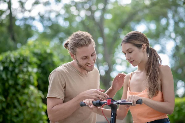 Young man checking settings on his girlfriends scooter — Stock Photo, Image