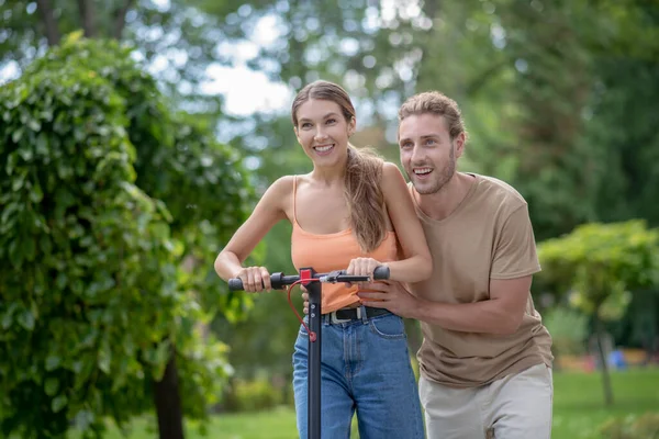 Junger Mann bringt seiner Freundin Rollerfahren bei — Stockfoto