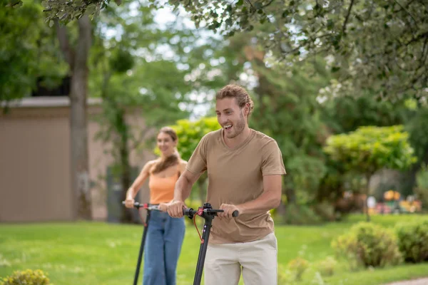 Zwei junge Leute fahren Roller im Park — Stockfoto