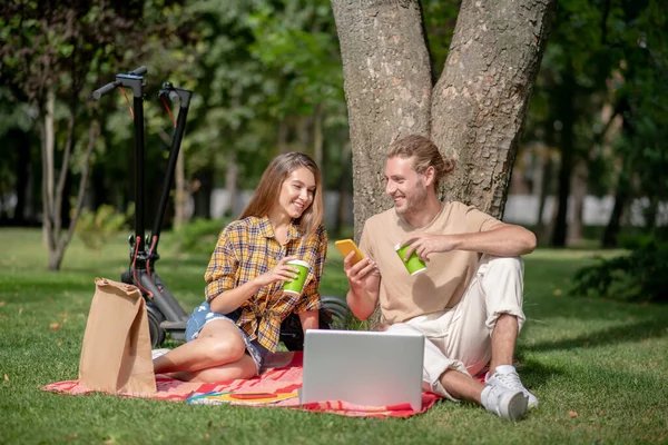 Young couple sitting under tree and enjoying the day — Stock Photo, Image
