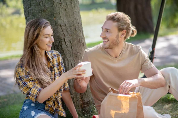 Jeune couple se reposant dans le parc et déjeunant ensemble — Photo