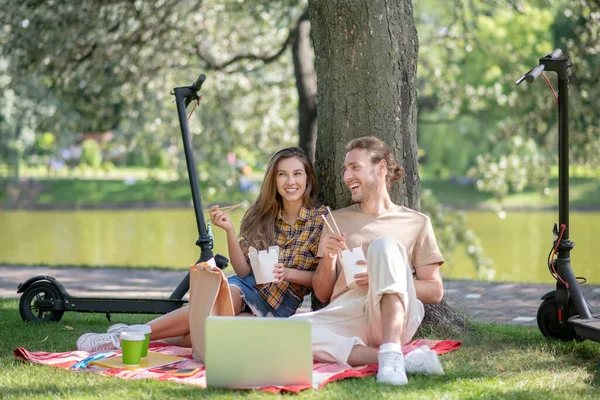 Young couple resting under the tree after lunch and feeling good — Stock Photo, Image
