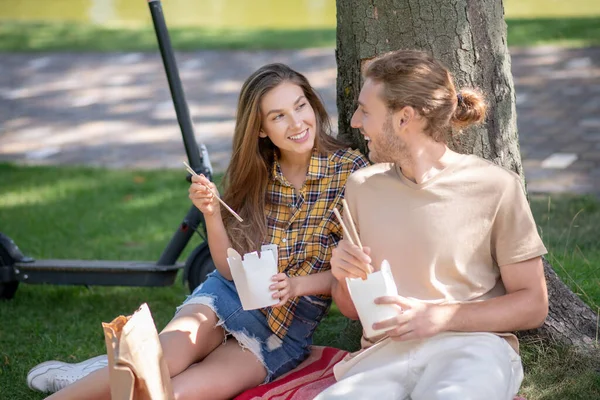 Young couple eating lunch and looking happy — Stock Photo, Image