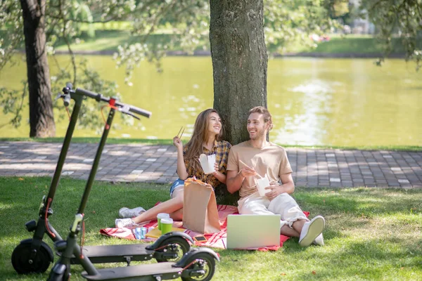 Junges Paar isst Mittagessen im Park und sieht friedlich aus — Stockfoto