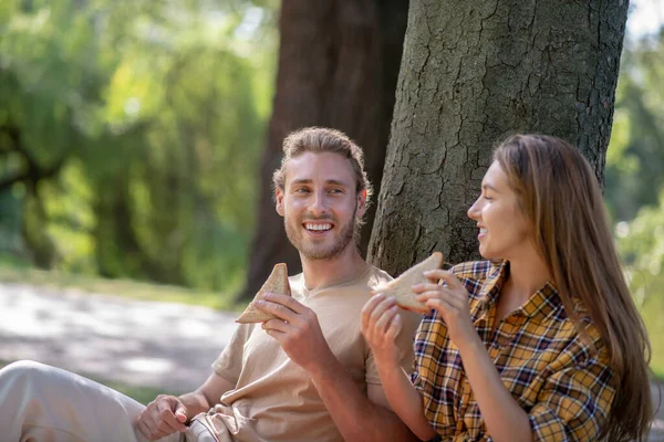 Jeune couple manger des sandwichs et regarder apprécié — Photo