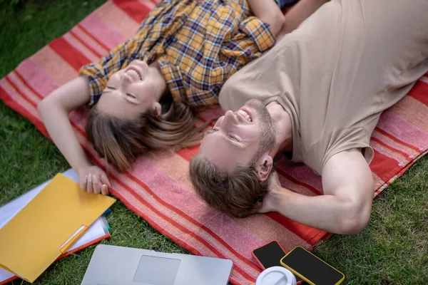 Joven pareja feliz tumbada en la hierba y relajante —  Fotos de Stock