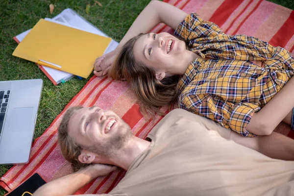 Joven pareja feliz tumbada en la hierba y relajándose juntos —  Fotos de Stock
