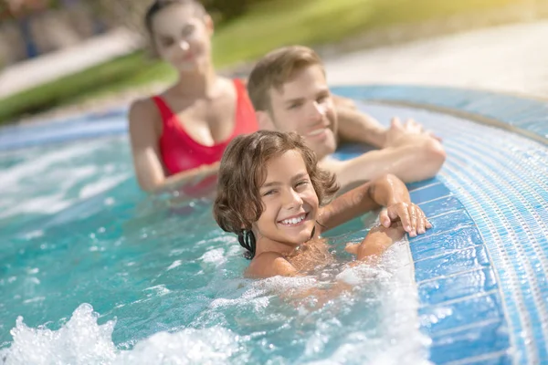 Menino feliz com pais na água da piscina — Fotografia de Stock