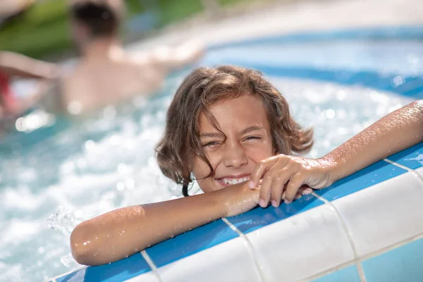 Joyful menino em idade escolar olhando para fora da piscina — Fotografia de Stock