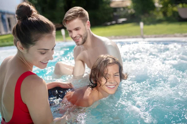 Föräldrar som lär ut simning till sin son i poolen — Stockfoto