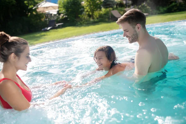 Smiling parents teaching their son to swim in the pool — Stock Photo, Image