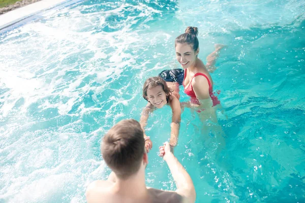 Padres felices enseñando a nadar a su hijo en la piscina —  Fotos de Stock