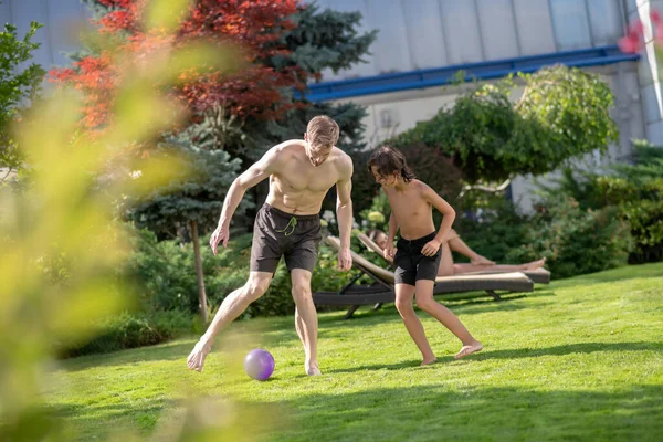 Hijo y papá jugando fútbol en el césped soleado — Foto de Stock