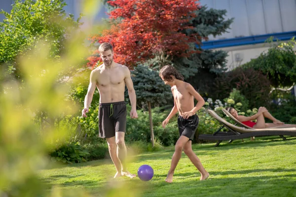 Homem e menino brincando com bola na grama — Fotografia de Stock