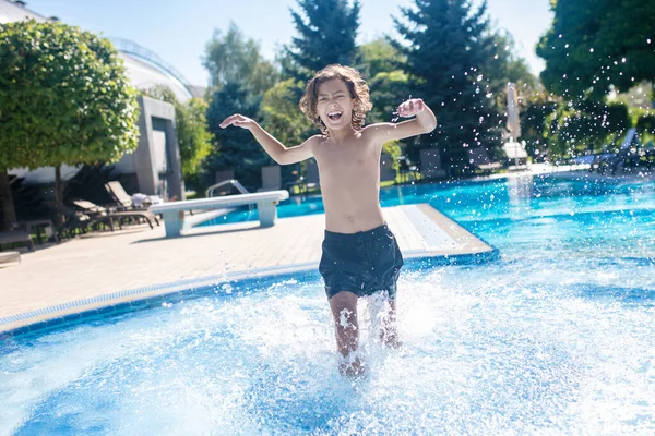 Rapaz entusiasmado a correr na piscina exterior — Fotografia de Stock