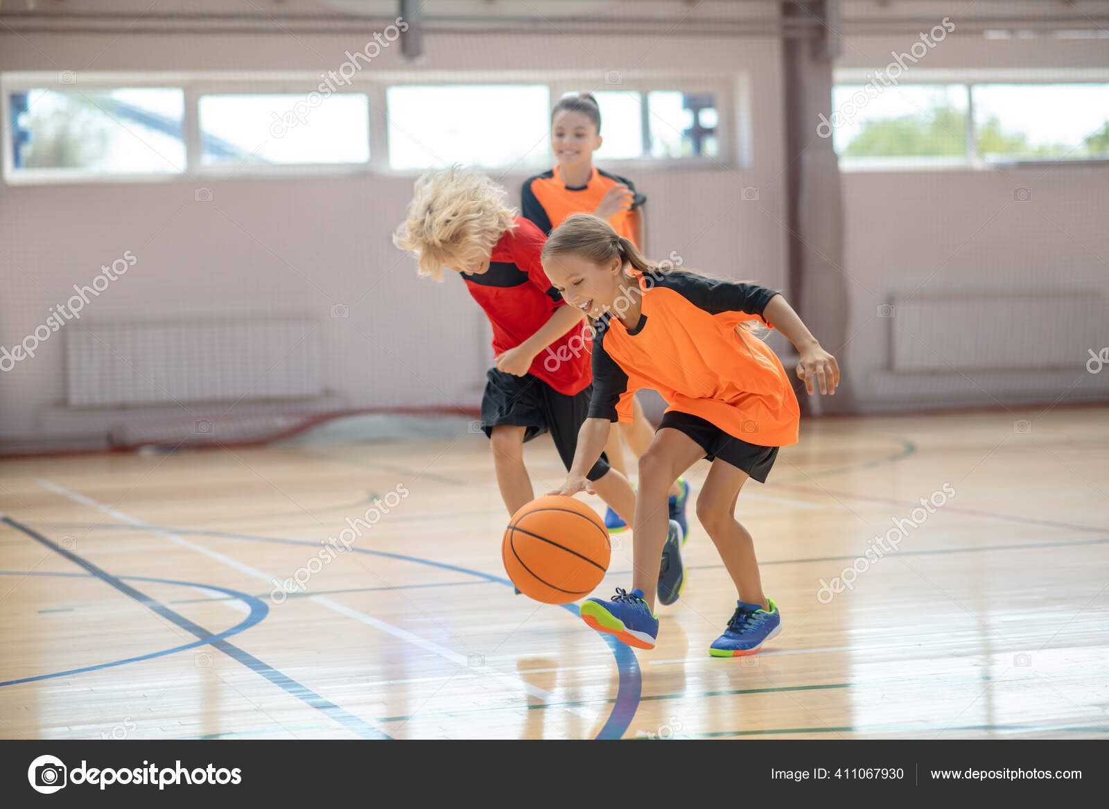 Ni os en ropa deportiva brillante jugando baloncesto en el