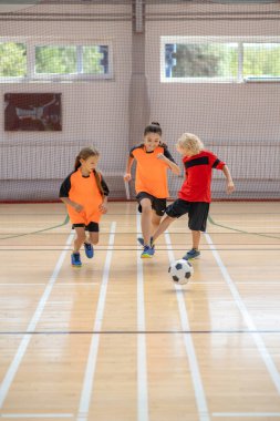 Spor giyim sektöründe üç çocuk spor salonunda futbol oynuyor.