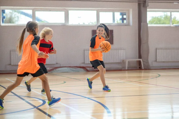 Niños en ropa deportiva brillante jugando baloncesto juntos y corriendo — Foto de Stock