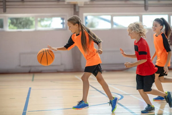 Niños en ropa deportiva brillante jugando baloncesto juntos y sintiéndose energizados — Foto de Stock