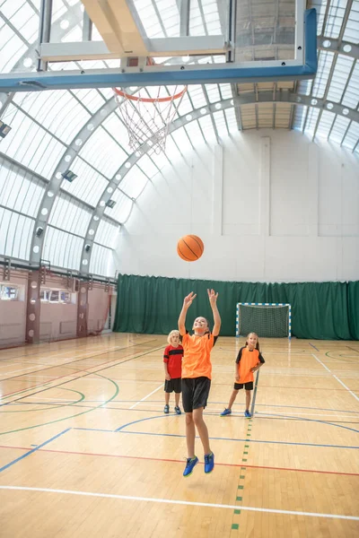 Una chica en camiseta naranja lanzando la pelota a la cesta — Foto de Stock